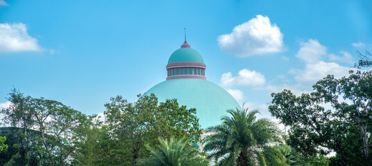 A large green dome emerges over the tropical vegetion of Krathing Lai beach near Pattaya, Thailand