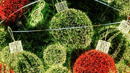 Festive Christmas lights shaped as ornaments and musical notes on a green fir tree. Bright red and golden decorations create a joyful holiday atmosphere, winter celebration background.