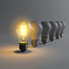 Single illuminated lightbulb stands out in a row of identical, unlit bulbs