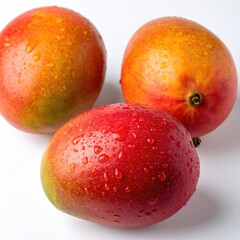 Three ripe mangos, covered in water droplets, sit clustered together against a plain white background