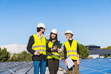 Team of diverse engineers inspecting solar panel installation on a rooftop, planning renewable energy generation