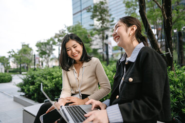 Authentic candid positive laughing two asian businesswoman enjoy talking at outdoors