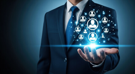 Professional man in a dark blue suit holds a glowing digital network of diverse human icons with a bright blue light beam over a dark blue gradient background, symbolizing connections and teamwork.