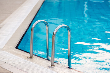 Ladder stainless handrails for descent into swimming pool.