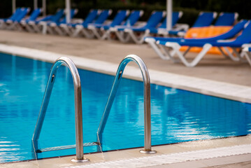 Steel railings stairs in a pool with a blue water