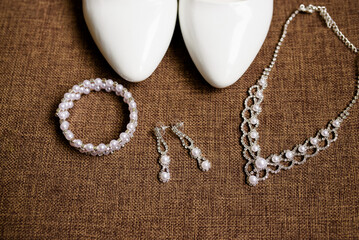 Women's handbag, shoes and jewelry on a light marble background. Top view. Place for text.