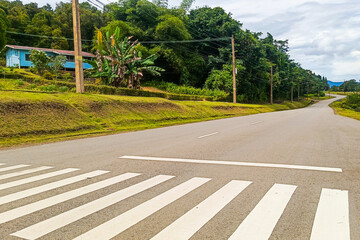 There is a zebra crossing. The road is paved and a house is visible.