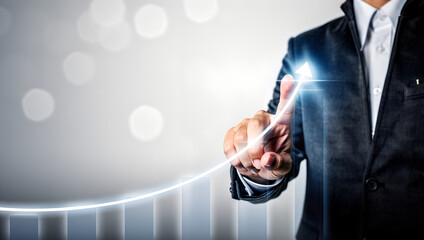 Businessman points to a glowing upward trend line representing business growth and success