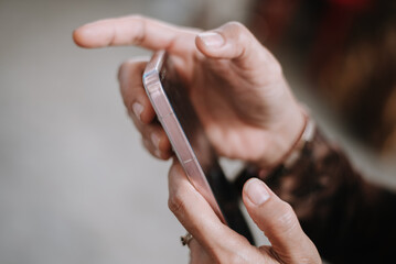 Obraz premium Close-Up Of Hands Holding A Pink Smartphone With Focused Gesture