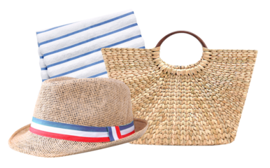 low-angle photograph of a straw sun hat with a striped band, a folded striped towel, and a woven straw bag isolated against a black backdrop