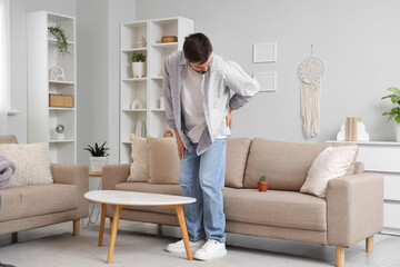 Young man with hemorrhoids and cactus on sofa at home
