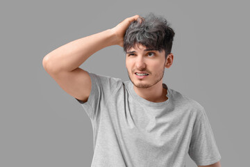 Worried young man with graying hair on light background