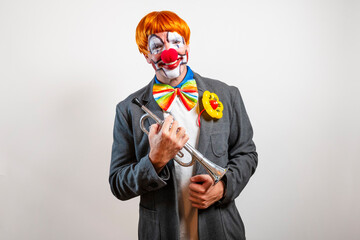 Clown with red wig and costume holding trumpet