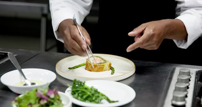 Culinary, plating or hands in restaurant with tweezers, catering or presentation in luxury cuisine. Hospitality, expert or chef in kitchen with tool, preparation or food decorating in fine dining