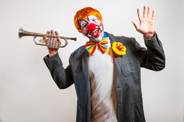 Clown playing trumpet and waving against white background