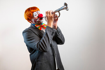 Clown with red nose playing trumpet for performance
