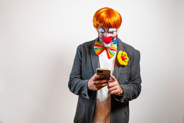 Sad clown in suit looking at smartphone