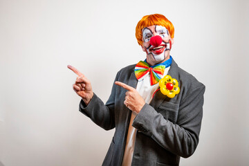 Happy clown pointing left and smiling on white background
