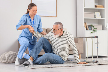 Nurse helping senior man after fall with walker at home