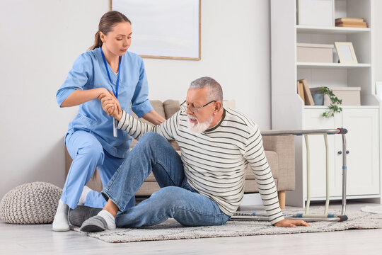Nurse helping senior man after fall with walker at home