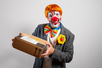 Clown delivering cardboard package with a funny expression