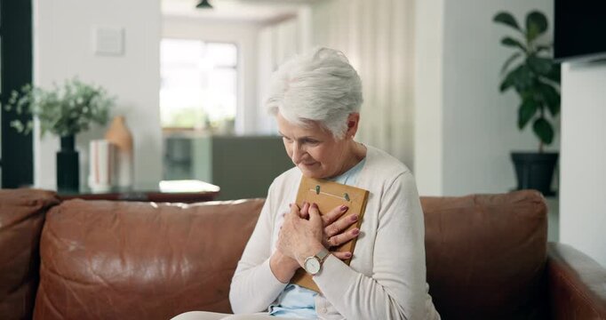 Sad, old woman and hug photo frame on sofa for partner loss, mourning or sorrow in retirement. Lonely widow, senior person with depression or embrace picture in home for memory, broken heart or grief