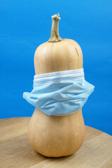 pumpkin wearing a face mask for protection from coronavirus with halloween face. Halloween and virus