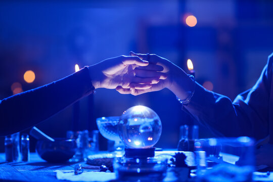 Fortune teller reading woman's palm at table