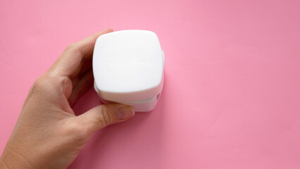 woman hands with cream cosmetic bottles on pink background, cold season hands skin protection. Top view