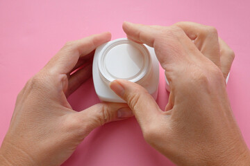 woman hands with cream cosmetic bottles on pink background, cold season hands skin protection. Top view