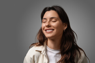 Fototapeta premium Happy young woman with nose, lip and ear piercing on grey background