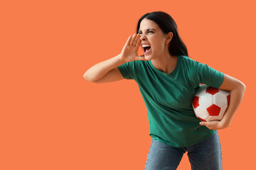 Female soccer fan with ball shouting on orange background