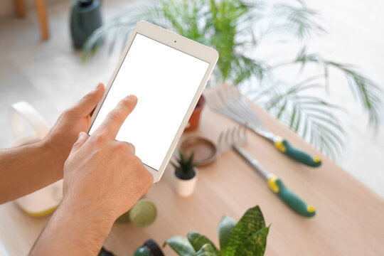 Male gardener's hands using blank tablet computer in workshop, closeup - Powered by Adobe