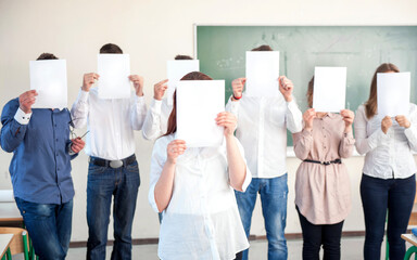 College students holding blank paper sheets in classroom