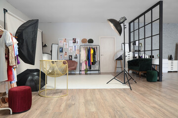 Interior of photo studio with professional equipment, clothes rack and folding screen