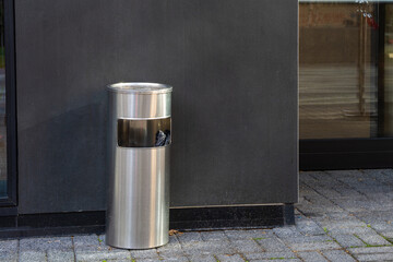 A large, freestanding metal ashtray, the type commonly placed in front of hotels or public buildings. Urban street furniture for smokers.

