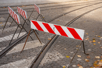 Road closure and blockade signs irregularly arranged on a street, indicating construction work or a closed roadway.

