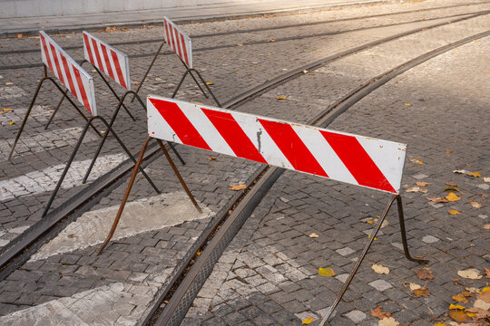Road closure and blockade signs irregularly arranged on a street, indicating construction work or a closed roadway.

