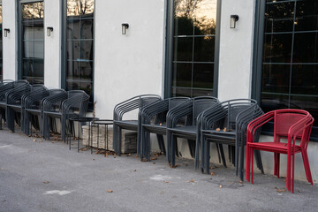 Metal chairs stacked in front of a currently closed restaurant. Neatly arranged seating equipment in an urban outdoor setting.


