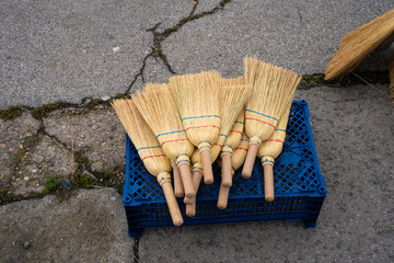 A pile of reed brooms. Cleaning tools made from natural materials arranged together.

