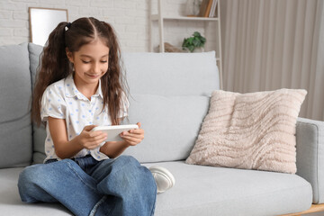 Obraz premium Cute girl using mobile phone on sofa at home