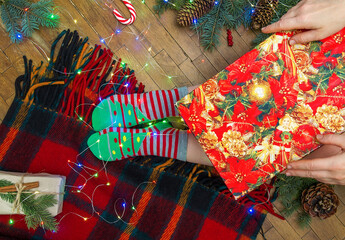 Christmas cozy flat lay with colorful wool blanket fairy lights and winter socks on wooden floor showing warm holiday home atmosphere