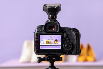 Stylish bags with shoes on camera screen in photo studio, closeup