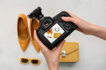 Female photographer with camera taking picture of accessories on white background, top view
