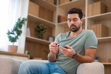 Young man checking blood sugar with glucometer at home