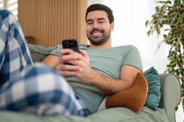 Man relaxing on couch using smartphone at home