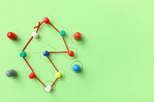 Connected pins with figures and thread on green background. Link concept - Powered by Adobe