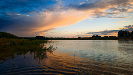 Naklejka premium Sunset on the cloudy river.