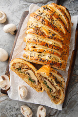 Vegan Mushroom Wellington features a mushroom and spinach filling and golden puff pastry closeup on the wooden board on the table. Vertical top view from above