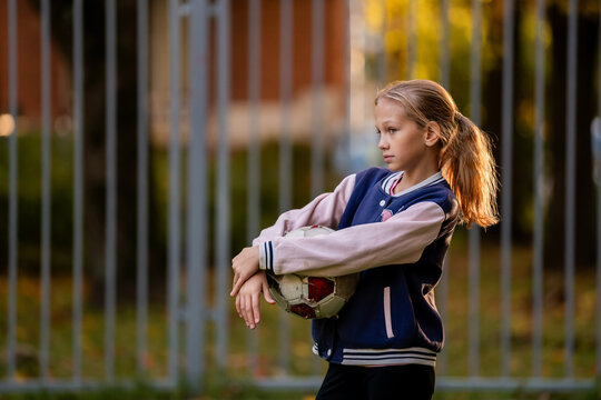 girl is holding a soccer ball on a soccer field in the yard.
